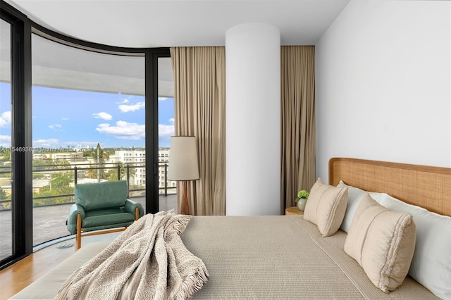 bedroom with wood-type flooring, a wall of windows, and access to exterior