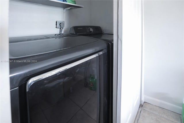 laundry area with independent washer and dryer and light tile patterned flooring