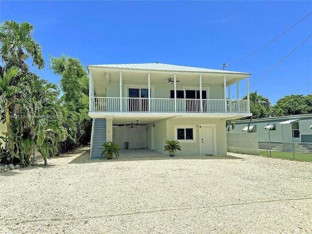 back of house with ceiling fan and a carport