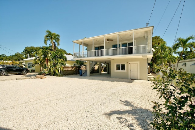 raised beach house featuring ceiling fan, a balcony, and a carport