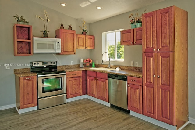 kitchen featuring stainless steel appliances, sink, and light wood-type flooring