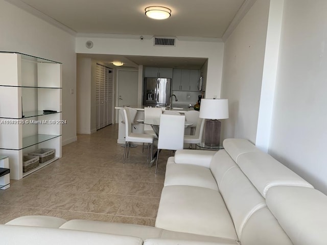 living room featuring ornamental molding, light tile floors, and sink