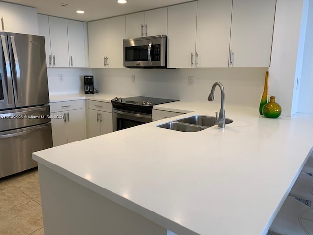 kitchen with kitchen peninsula, stainless steel appliances, white cabinets, and sink