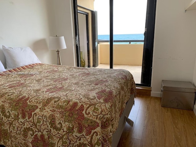 bedroom with a water view and light hardwood / wood-style floors