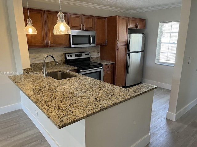 kitchen with pendant lighting, light wood-type flooring, appliances with stainless steel finishes, sink, and tasteful backsplash