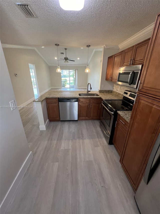 kitchen with decorative light fixtures, appliances with stainless steel finishes, kitchen peninsula, and crown molding