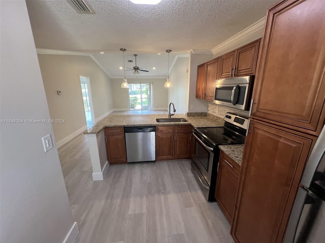 kitchen featuring appliances with stainless steel finishes, sink, crown molding, kitchen peninsula, and pendant lighting