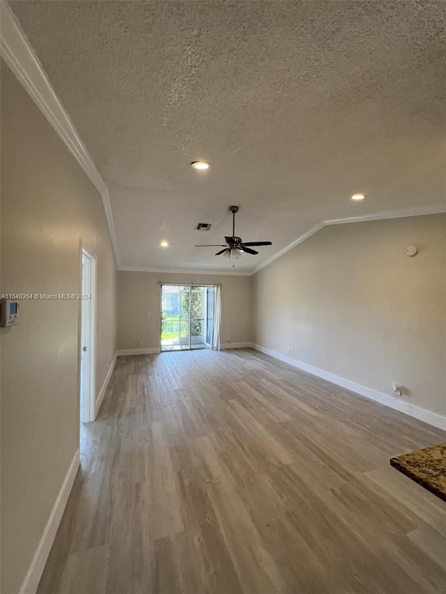 spare room with ceiling fan, crown molding, lofted ceiling, a textured ceiling, and light wood-type flooring