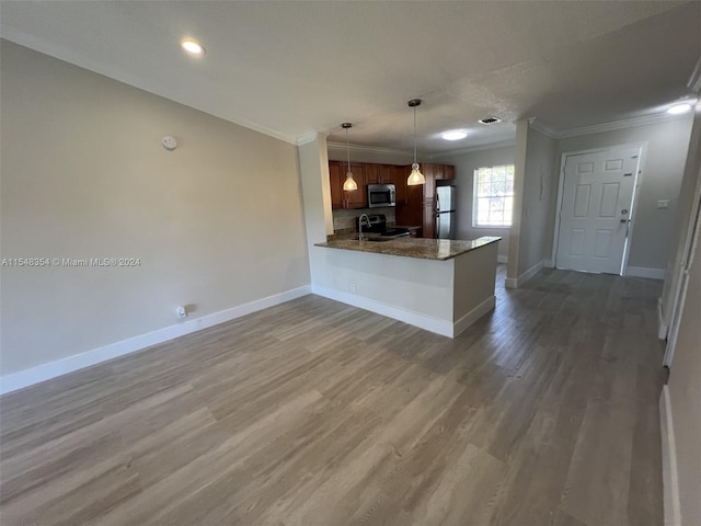 kitchen with kitchen peninsula, appliances with stainless steel finishes, dark wood-type flooring, dark stone counters, and ornamental molding