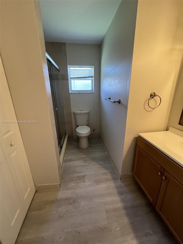 bathroom with wood-type flooring, vanity, toilet, and walk in shower