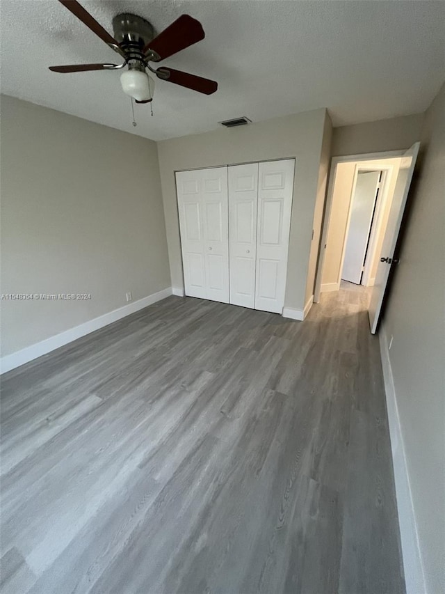 unfurnished bedroom featuring a closet, ceiling fan, light wood-type flooring, and a textured ceiling