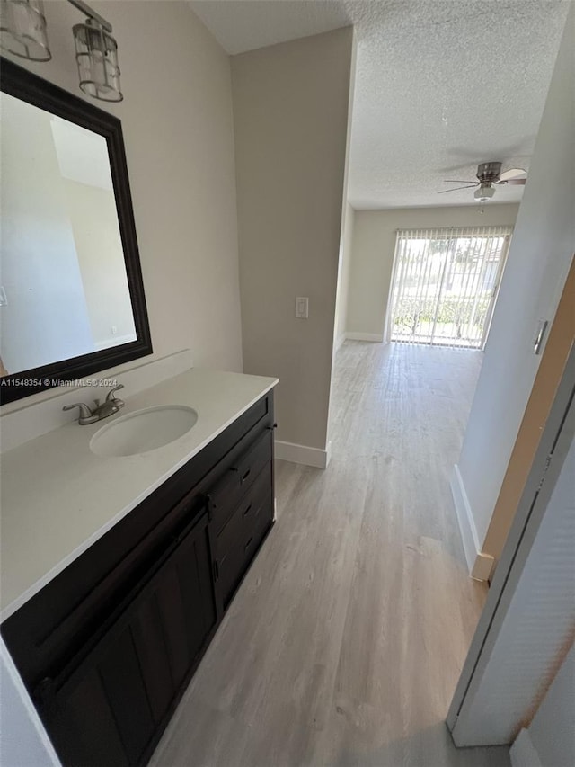 bathroom featuring hardwood / wood-style flooring, ceiling fan, vanity, and a textured ceiling