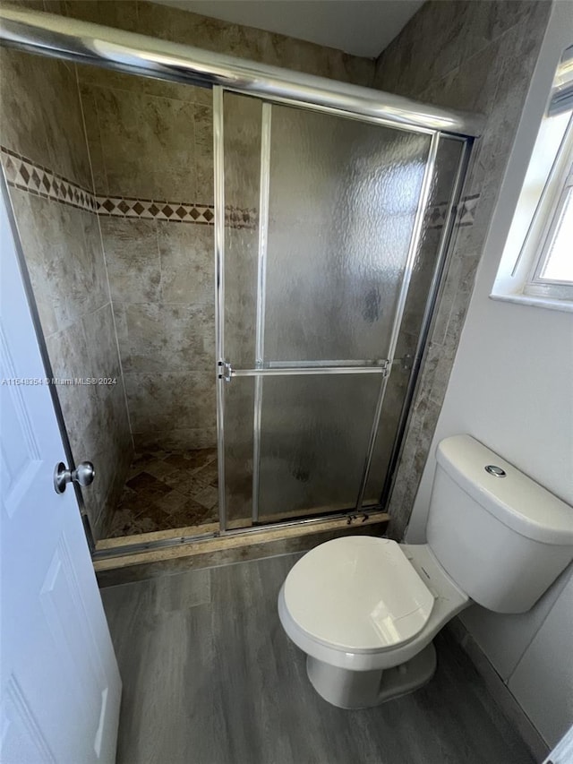 bathroom featuring walk in shower, wood-type flooring, and toilet