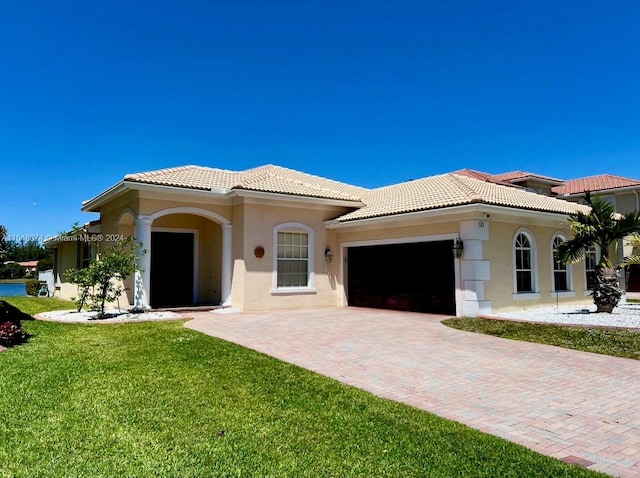 mediterranean / spanish-style home with a garage and a front lawn