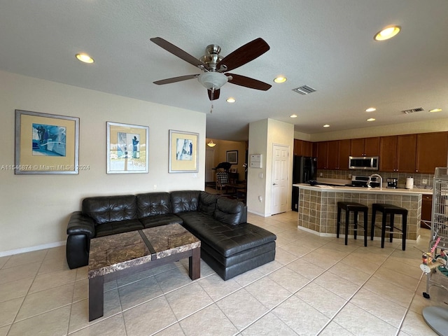 living room featuring sink, light tile patterned flooring, and ceiling fan