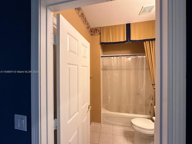 bathroom featuring tile patterned flooring, toilet, shower / bath combination with curtain, and a textured ceiling