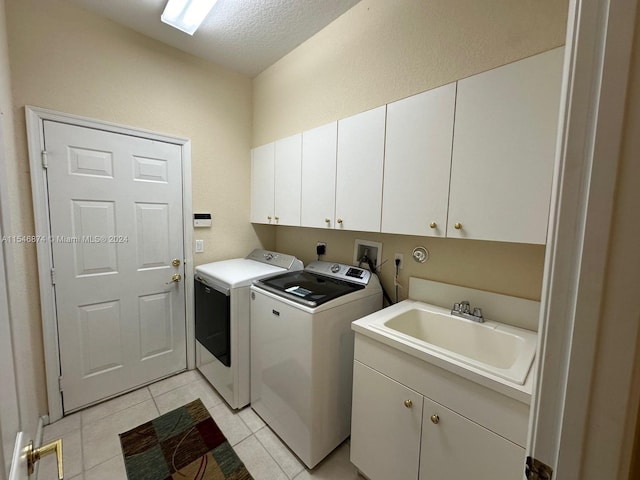 clothes washing area featuring sink, cabinets, light tile patterned floors, and washing machine and clothes dryer