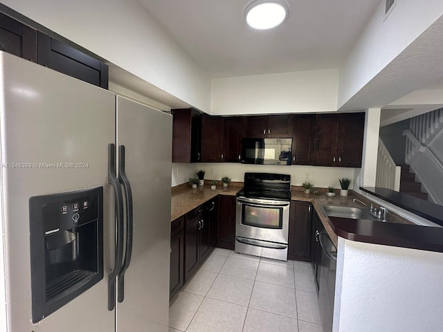 kitchen with dark brown cabinets, stainless steel appliances, light tile flooring, and sink