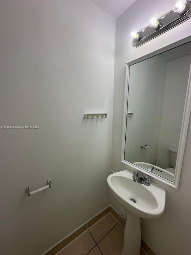 bathroom with toilet, tile flooring, and sink