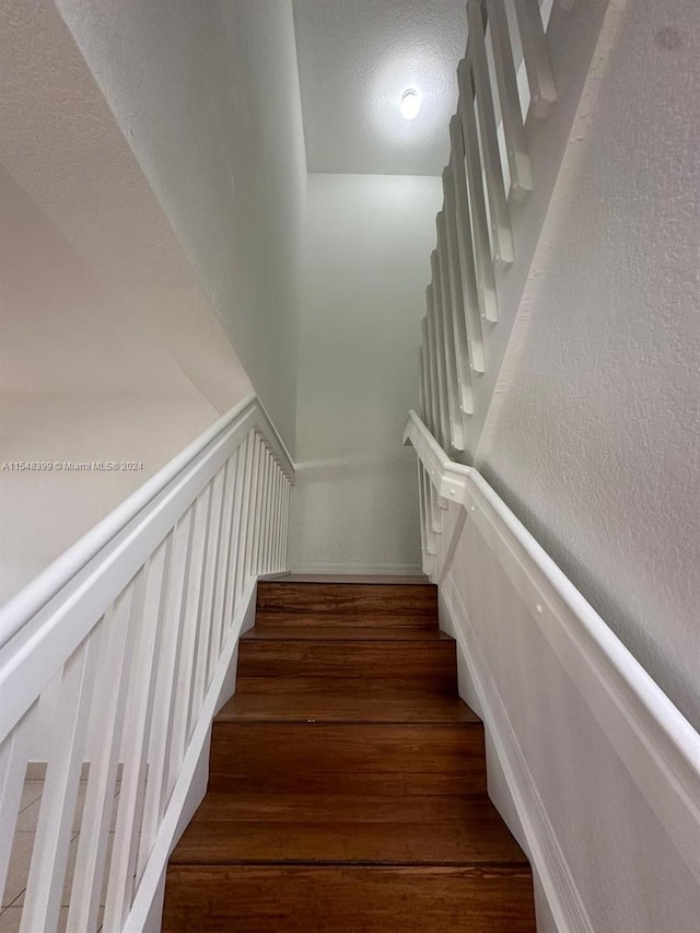 stairway with dark hardwood / wood-style floors and a textured ceiling