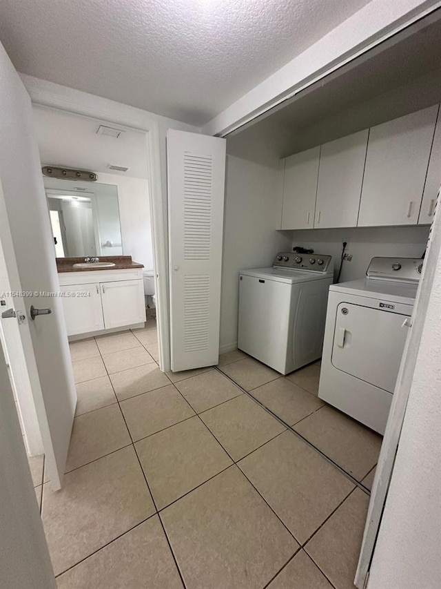 laundry area featuring independent washer and dryer, light tile floors, cabinets, and sink