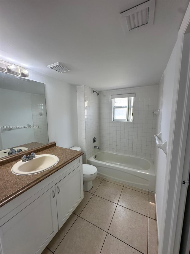 full bathroom featuring tiled shower / bath, toilet, tile floors, and vanity