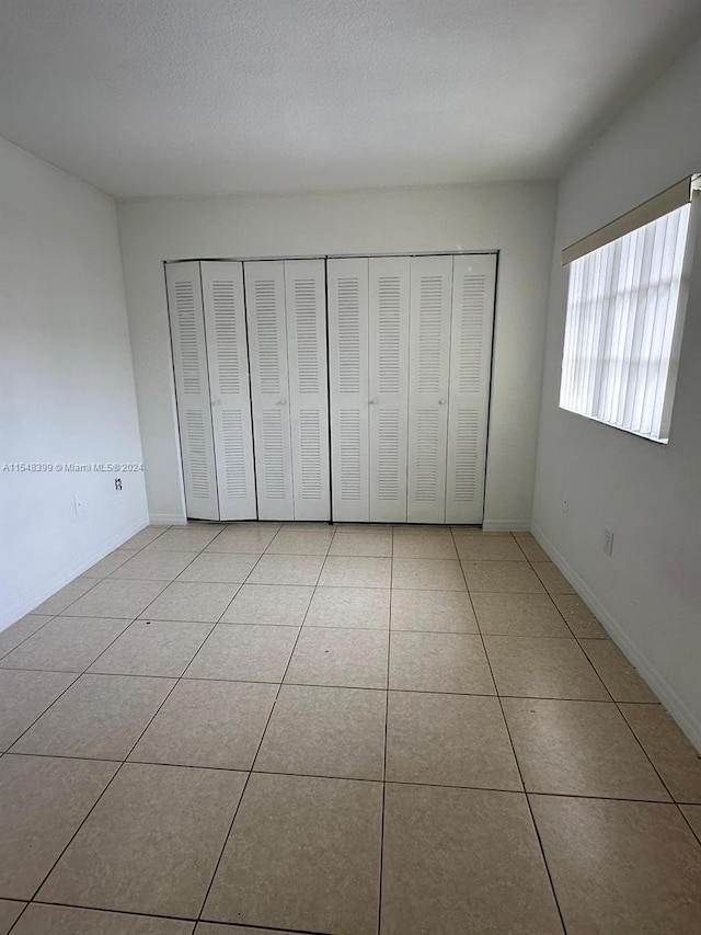 unfurnished bedroom featuring a textured ceiling and light tile flooring