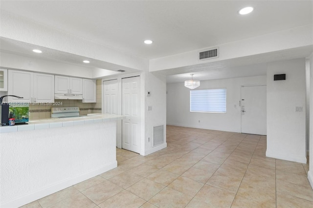 kitchen featuring white cabinets, light tile flooring, tasteful backsplash, white electric stove, and tile countertops