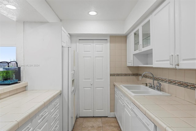 kitchen featuring sink, white appliances, tasteful backsplash, white cabinetry, and tile countertops