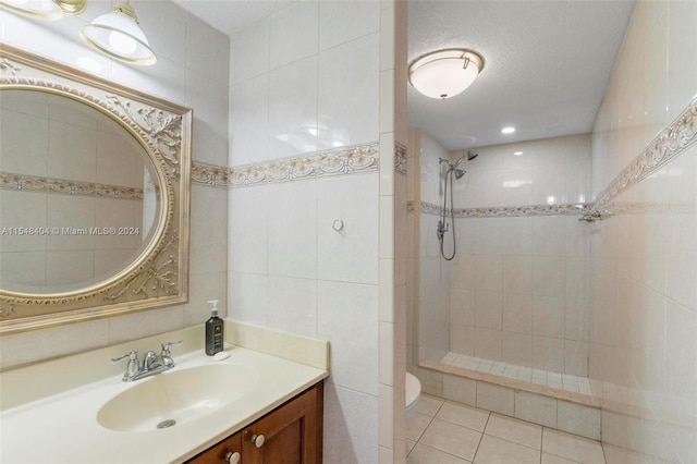 bathroom featuring tile walls, toilet, a textured ceiling, vanity, and tiled shower