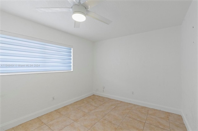 tiled empty room featuring ceiling fan