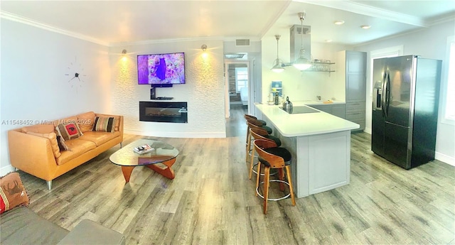 kitchen featuring kitchen peninsula, crown molding, decorative light fixtures, a breakfast bar, and black appliances