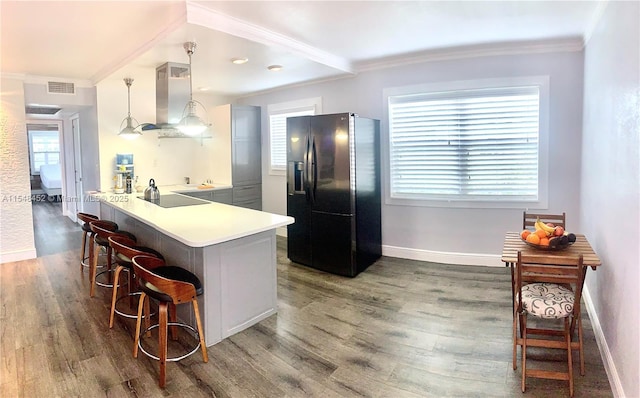 kitchen with pendant lighting, a breakfast bar, black appliances, island range hood, and kitchen peninsula