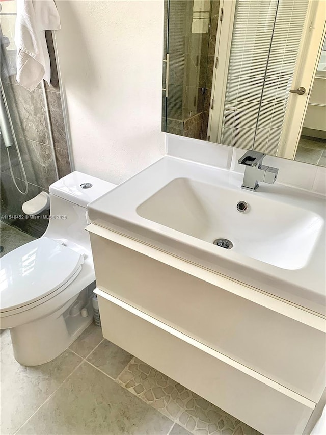 bathroom with toilet, vanity, and tiled shower