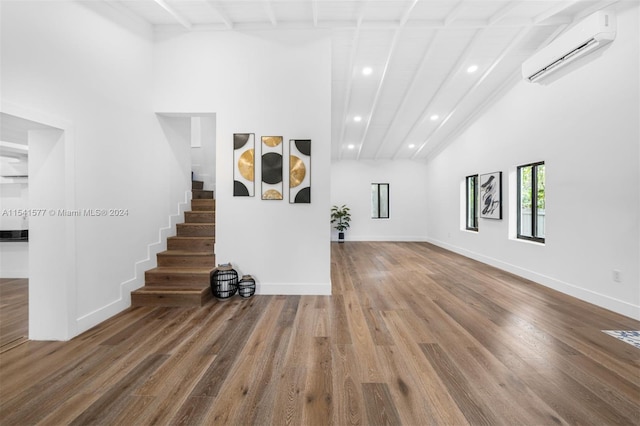 stairway with a wall mounted AC, high vaulted ceiling, hardwood / wood-style flooring, and beamed ceiling