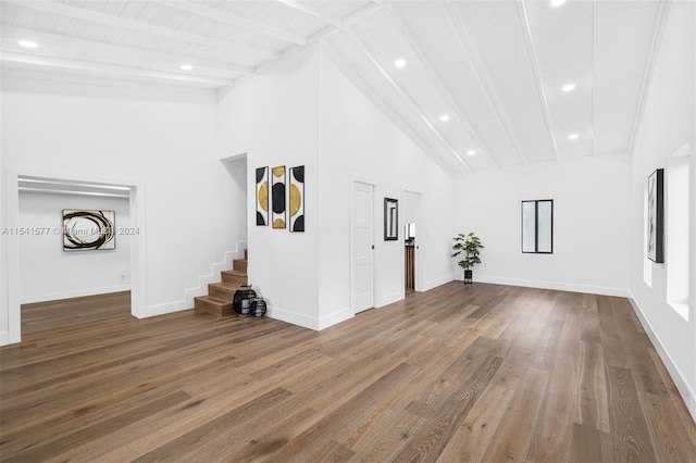 unfurnished living room featuring high vaulted ceiling, wood-type flooring, and beamed ceiling