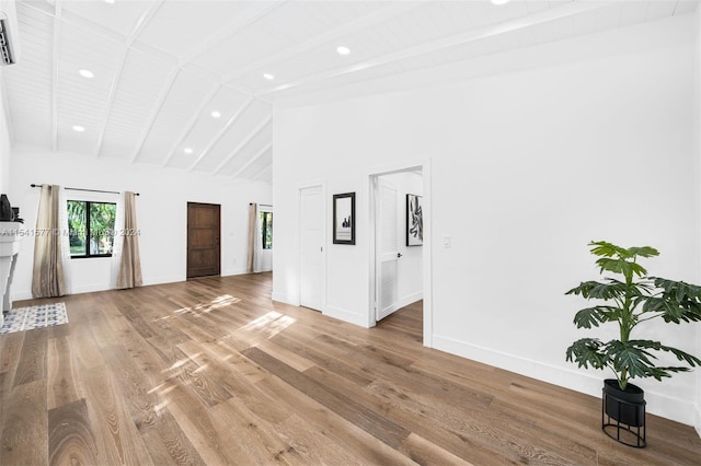 unfurnished living room featuring high vaulted ceiling, light wood-type flooring, and beam ceiling