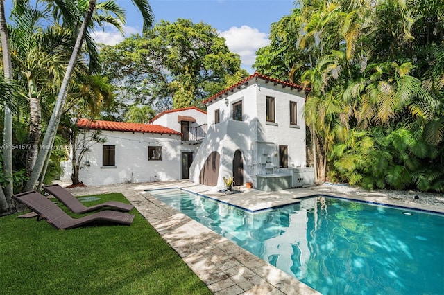 back of property featuring a patio area, an outdoor kitchen, and a lawn