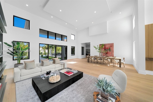 living room with light wood-type flooring and a towering ceiling