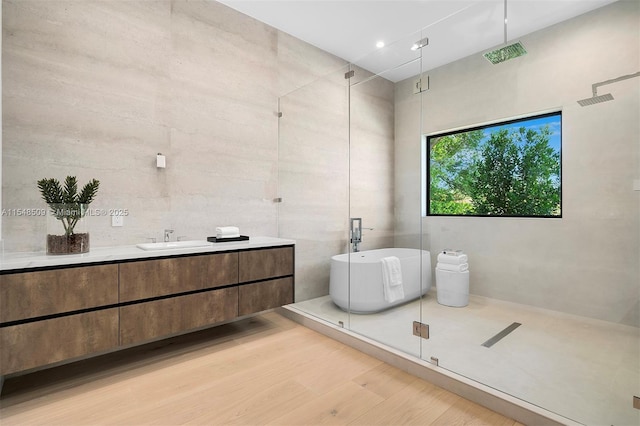 bathroom featuring vanity, wood-type flooring, tile walls, and shower with separate bathtub