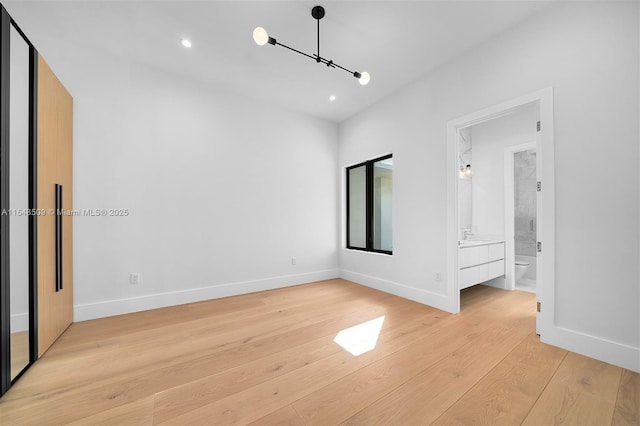 unfurnished bedroom featuring ensuite bath and light wood-type flooring