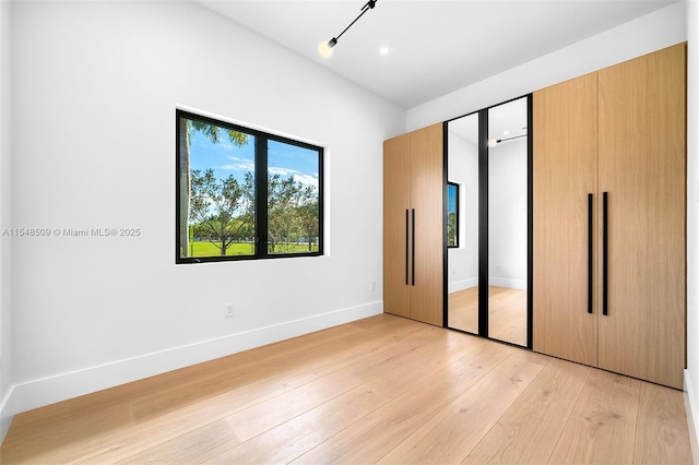 unfurnished bedroom featuring light wood-type flooring and a closet