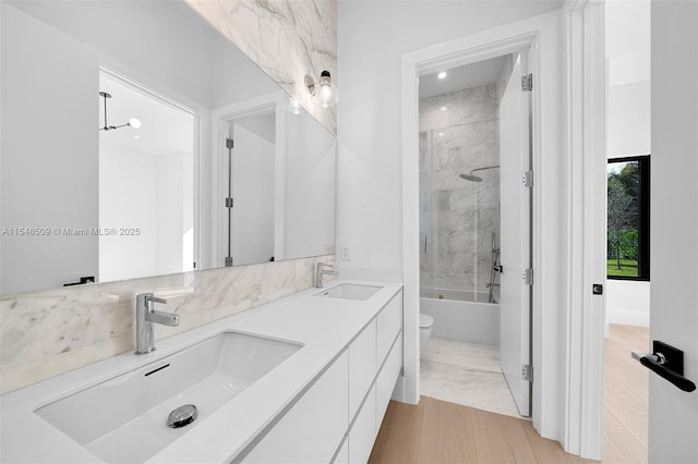 full bathroom with vanity, hardwood / wood-style flooring, tiled shower / bath, and toilet