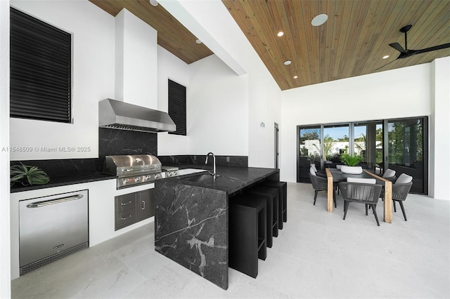 kitchen featuring a towering ceiling, refrigerator, ceiling fan, and wood ceiling