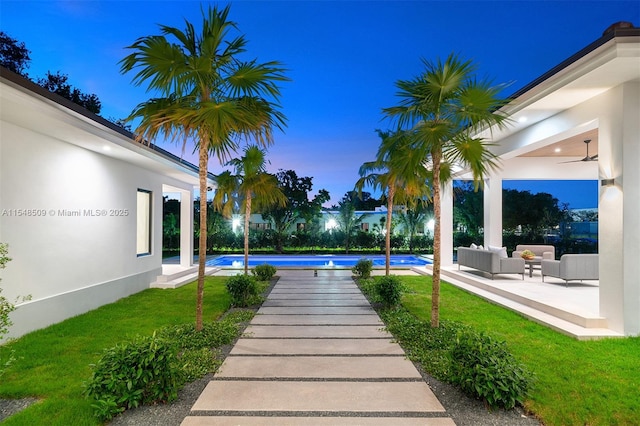 yard at dusk with outdoor lounge area, ceiling fan, and a patio area