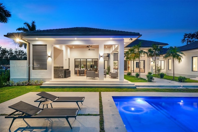 back house at dusk featuring ceiling fan, a patio, and an outdoor hangout area