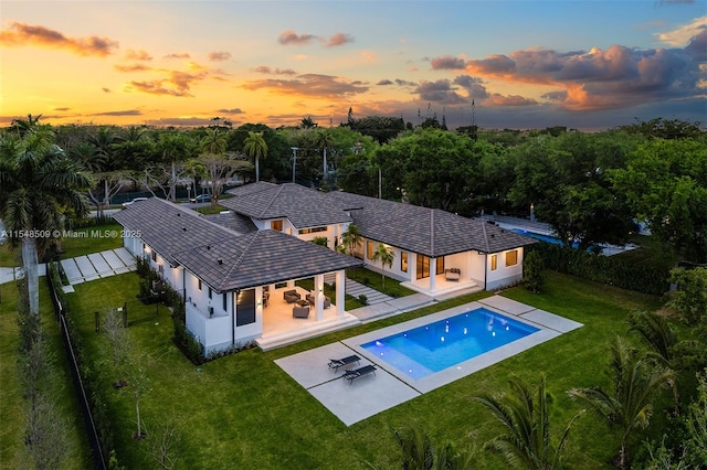 pool at dusk with a yard and a patio