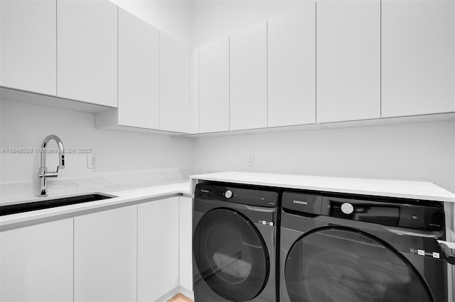 washroom with cabinets, sink, and washing machine and clothes dryer