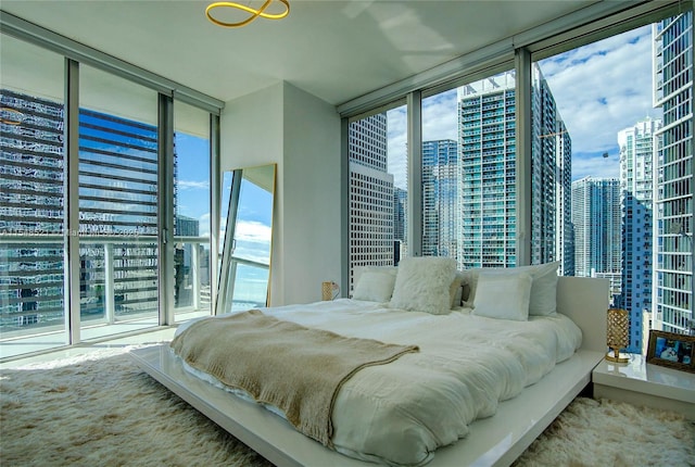 bedroom with multiple windows, a wall of windows, and a city view