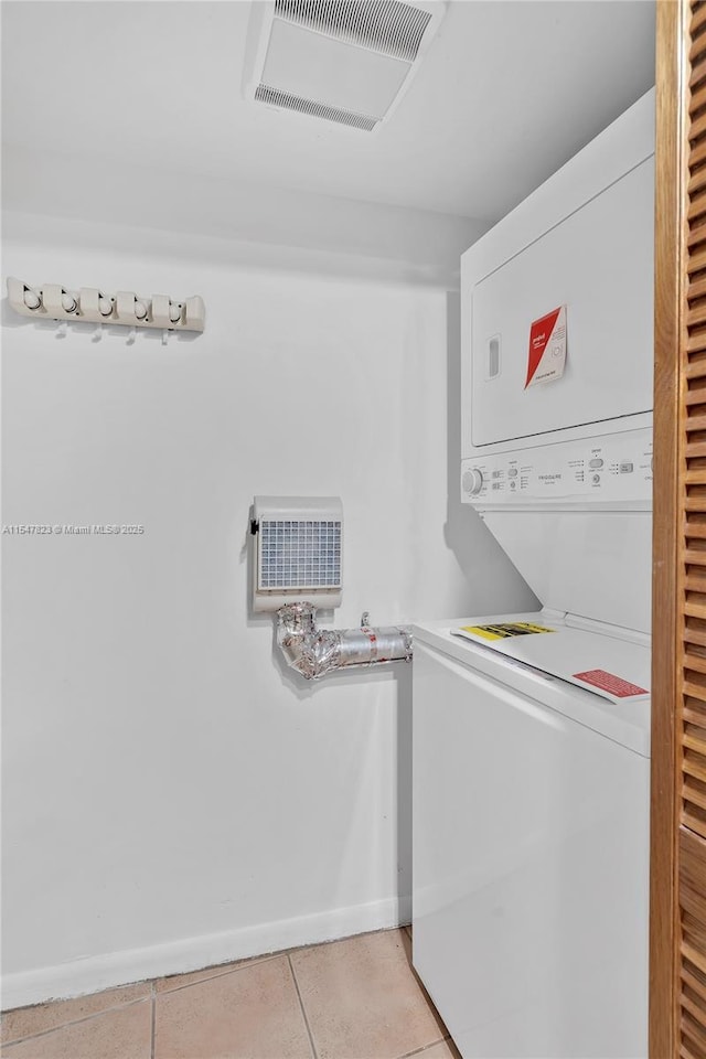 clothes washing area featuring light tile patterned floors and stacked washer / drying machine